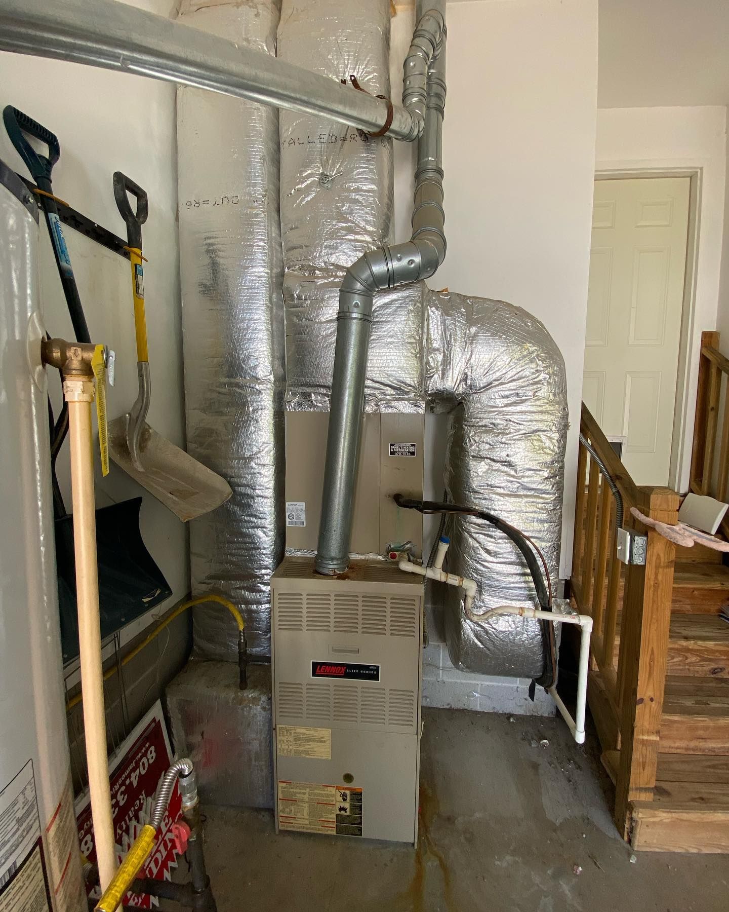 An air conditioner is sitting in a room next to a staircase.