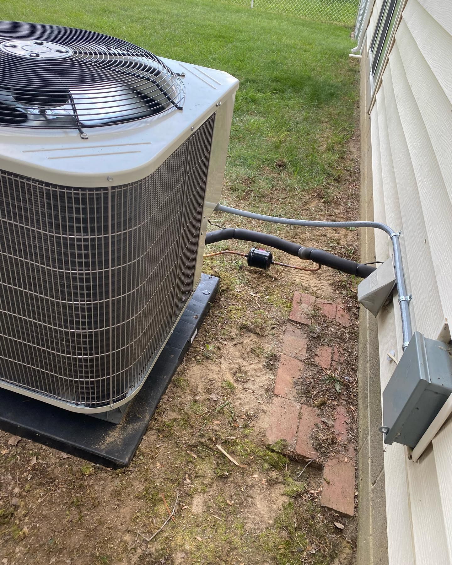 A large air conditioner is sitting on the side of a house.