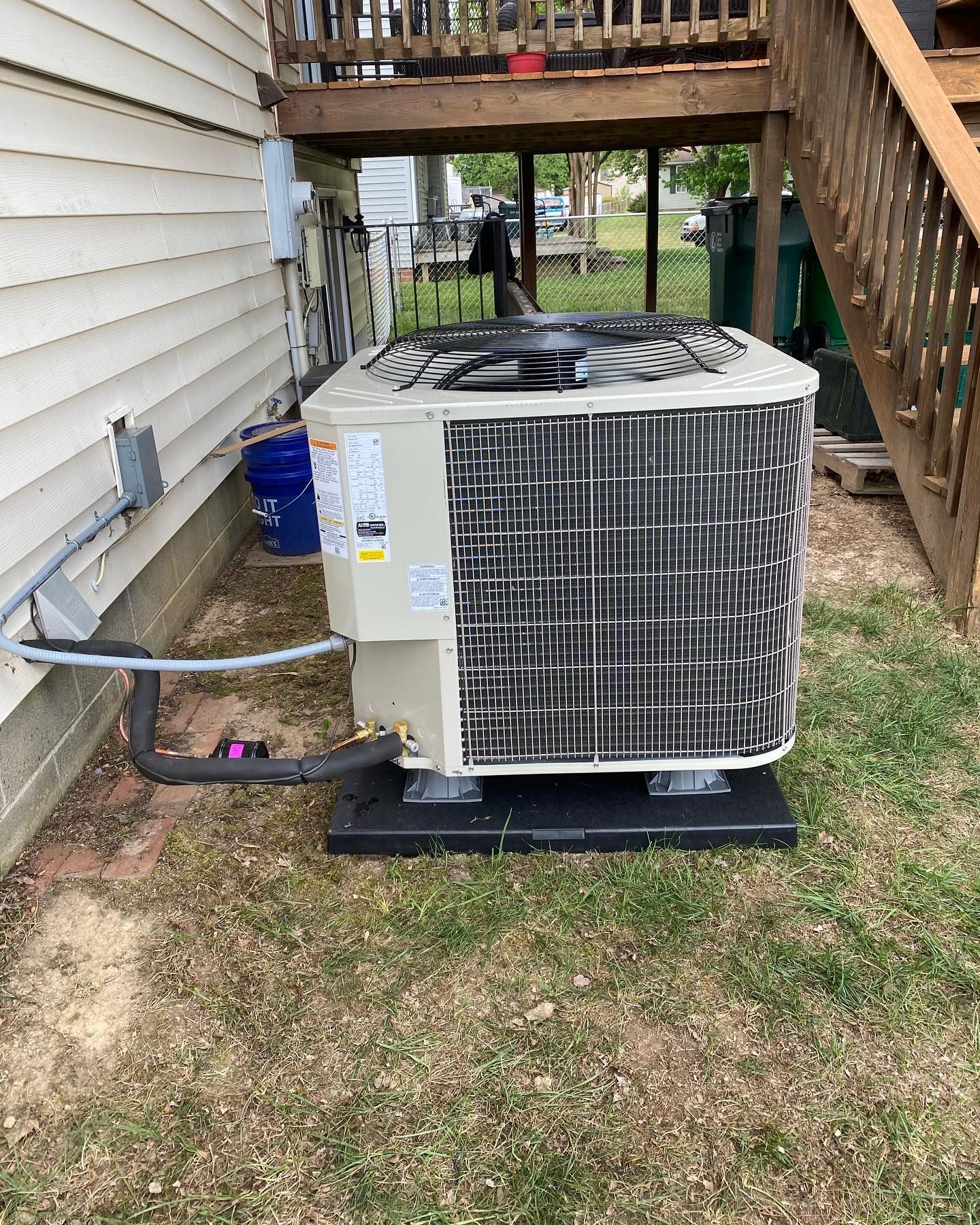 A large air conditioner is sitting in the grass next to a house.