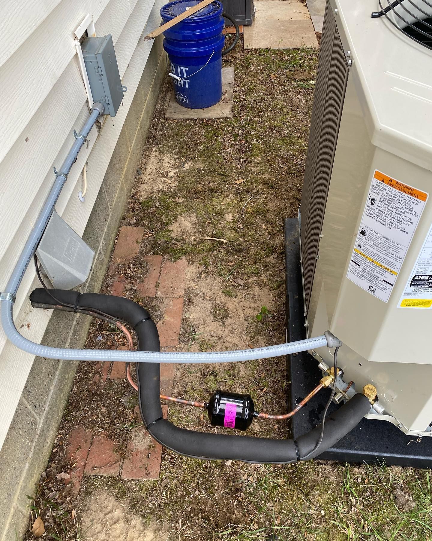 An air conditioner is being installed on the side of a house.