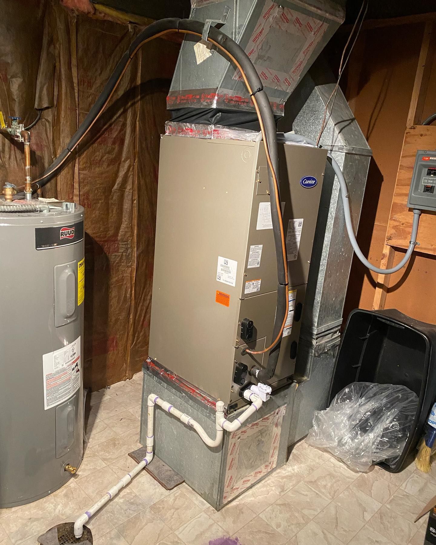 A water heater is sitting next to a furnace in a basement.