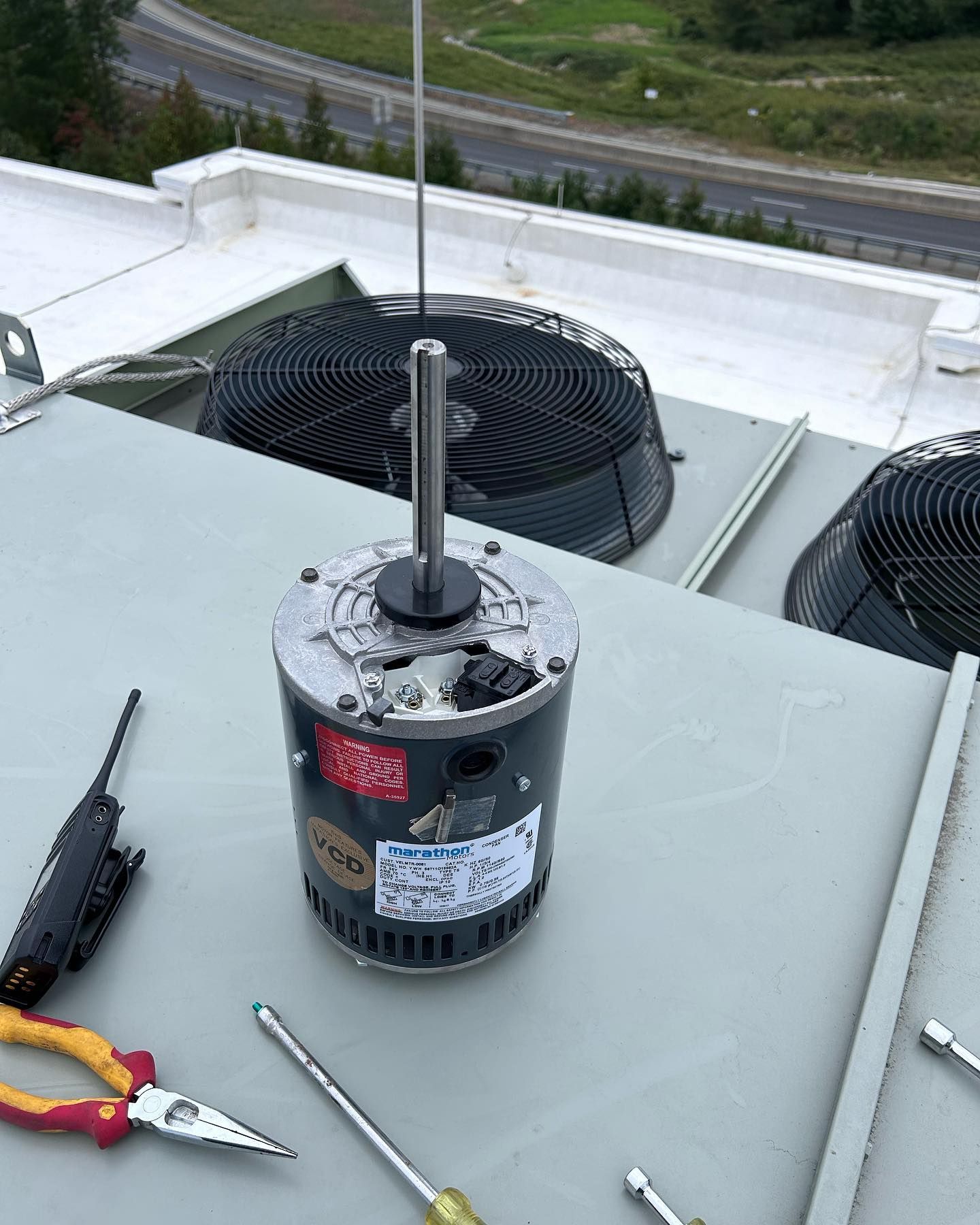 A motor is sitting on top of a table next to a pair of pliers.