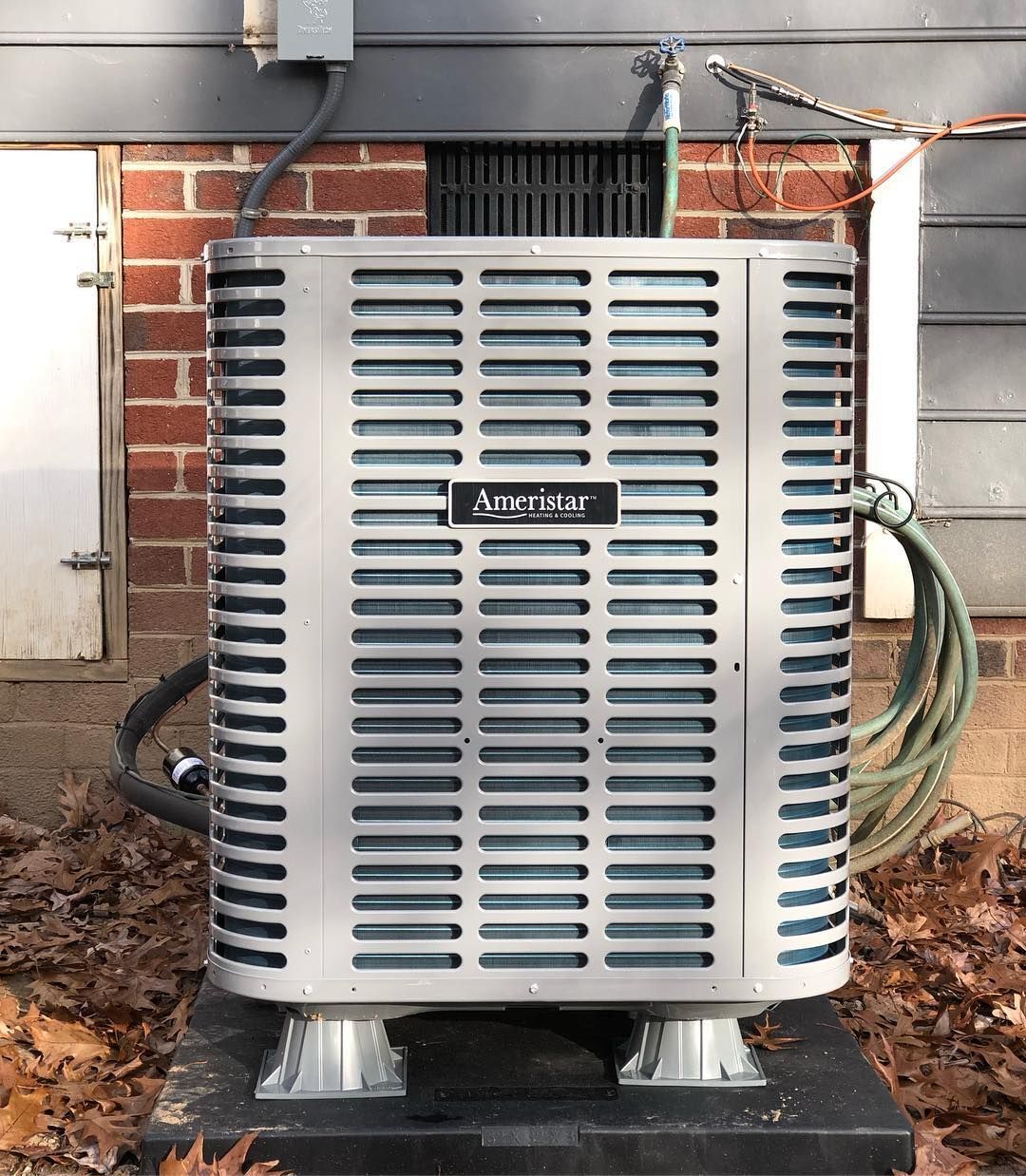 An air conditioner is sitting outside of a brick building.
