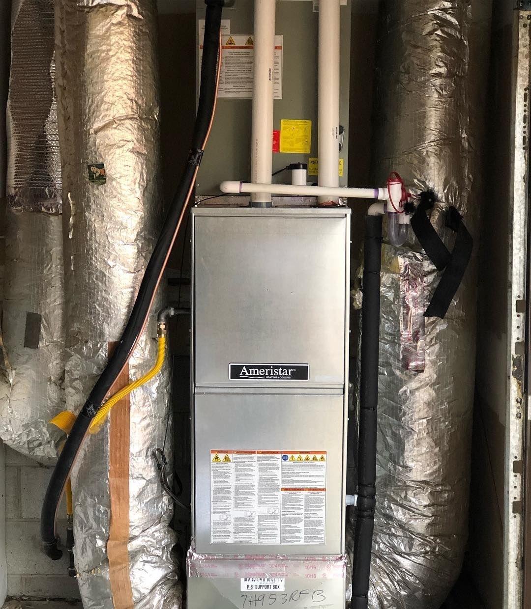 An air conditioner is sitting in a room with a lot of pipes.