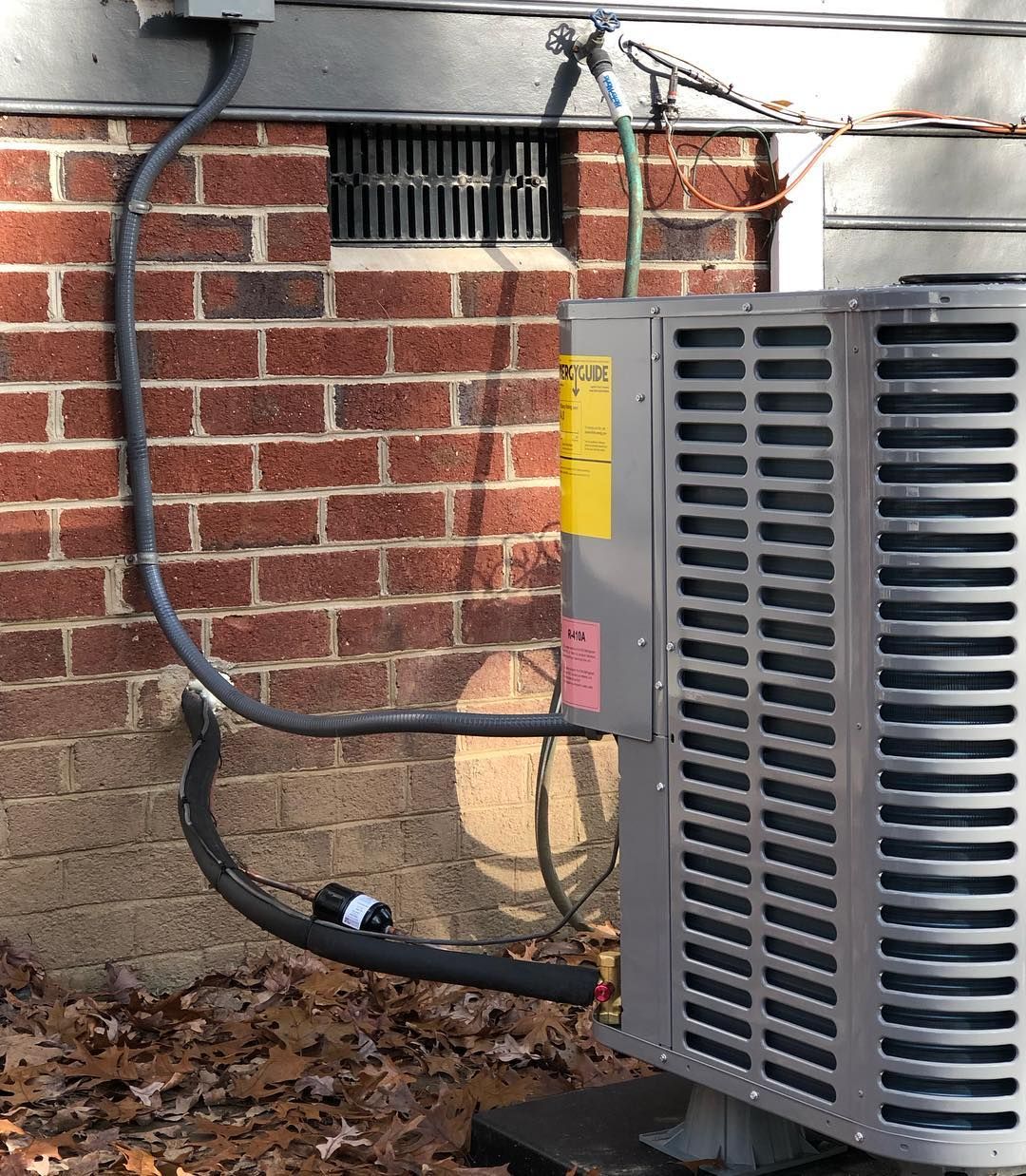 An air conditioner is attached to the side of a brick building.