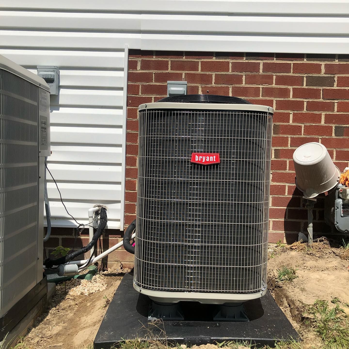 An air conditioner is sitting outside of a brick house.