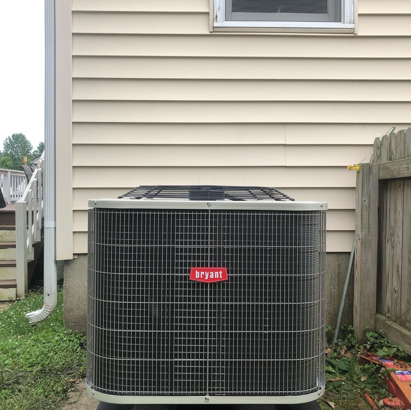 A bryant air conditioner is sitting outside of a house.
