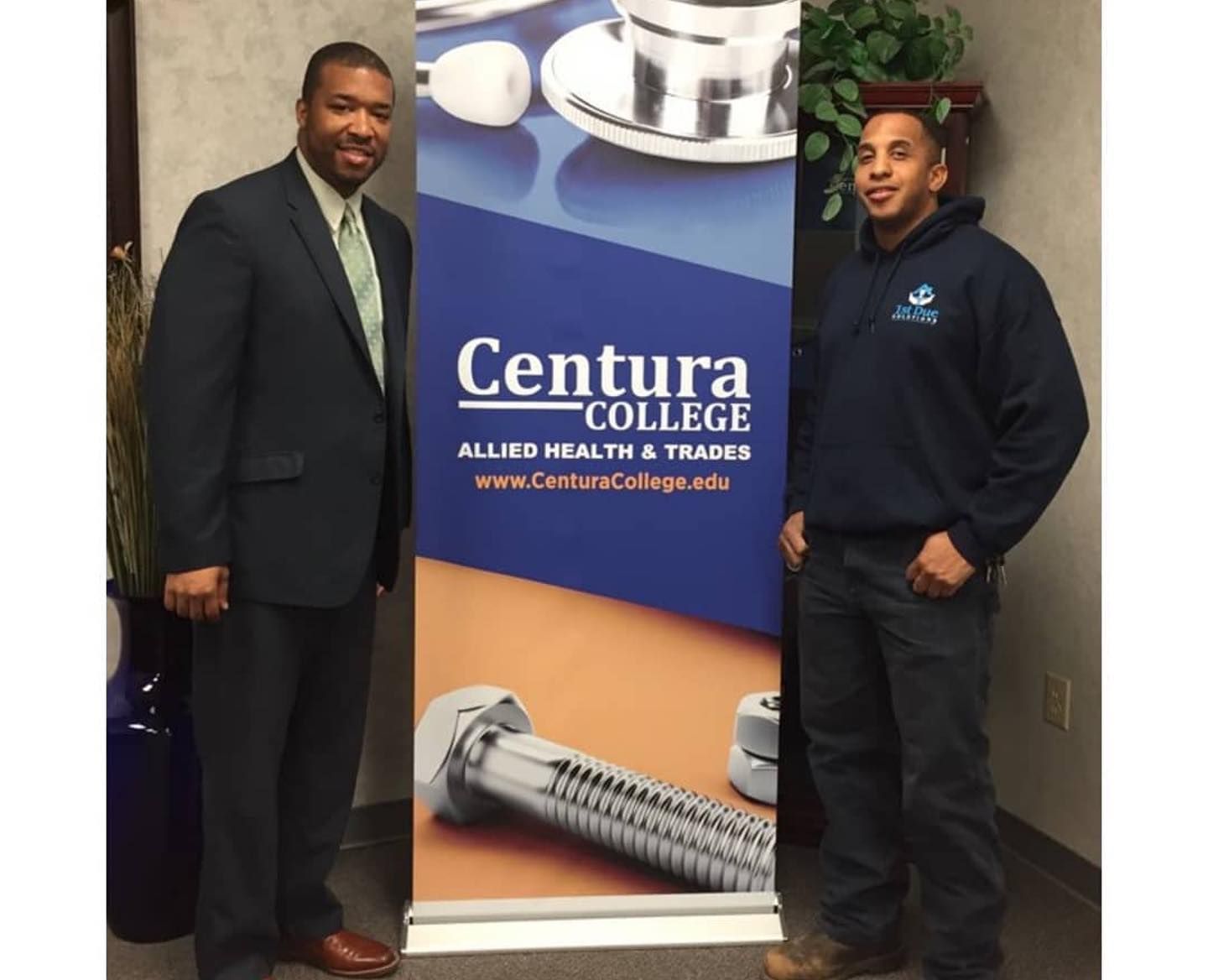 Two men standing next to a centura college banner