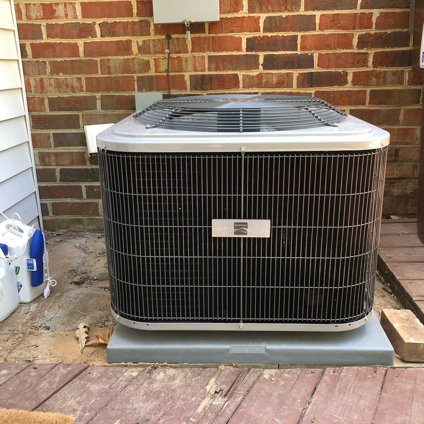 An air conditioner is sitting outside of a brick building.