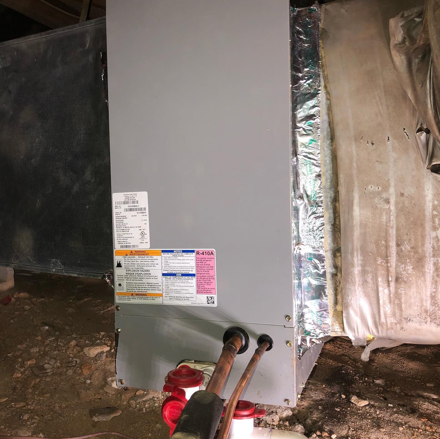 A water heater is sitting in a basement next to a wall.