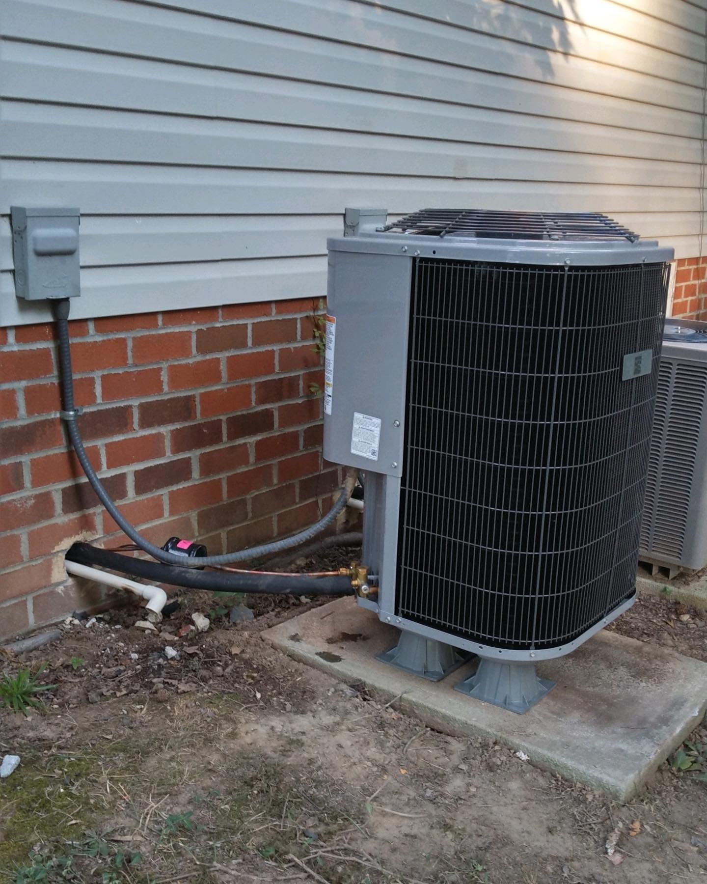 A couple of air conditioners are sitting on the side of a house.