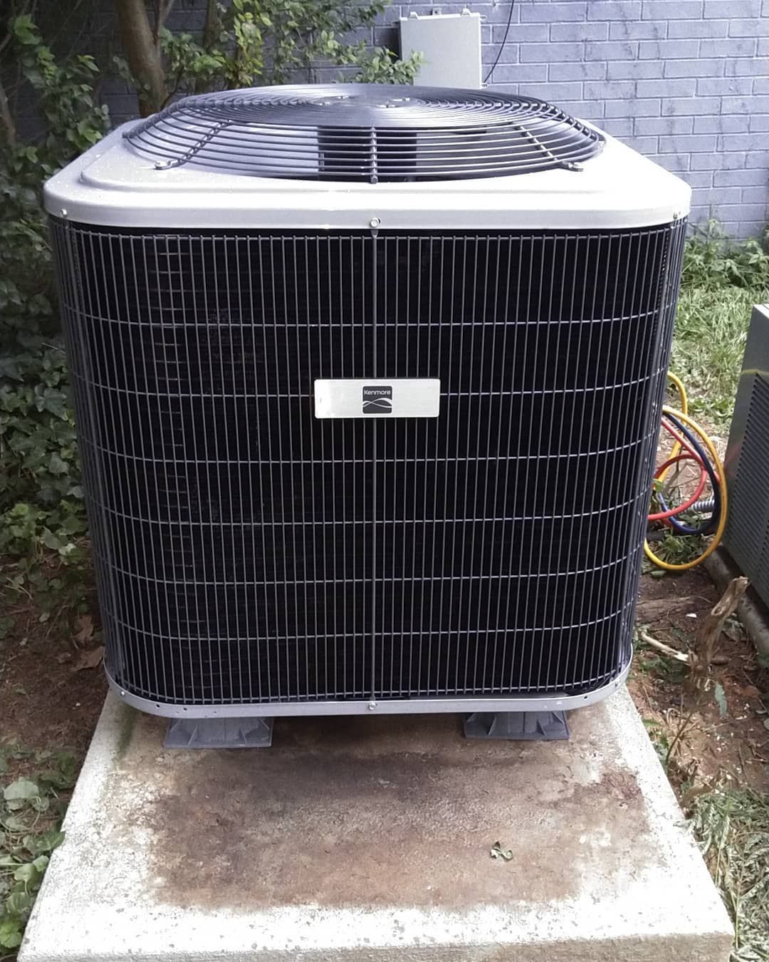 A large air conditioner is sitting on top of a concrete block.