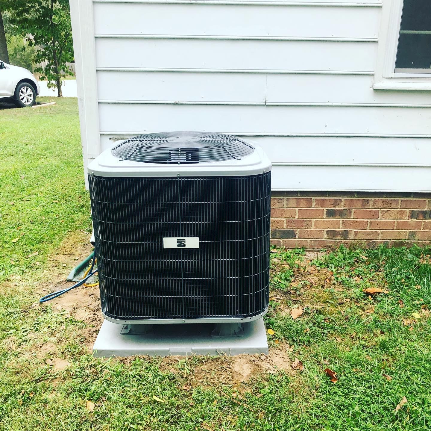 A black air conditioner is sitting on the side of a house.