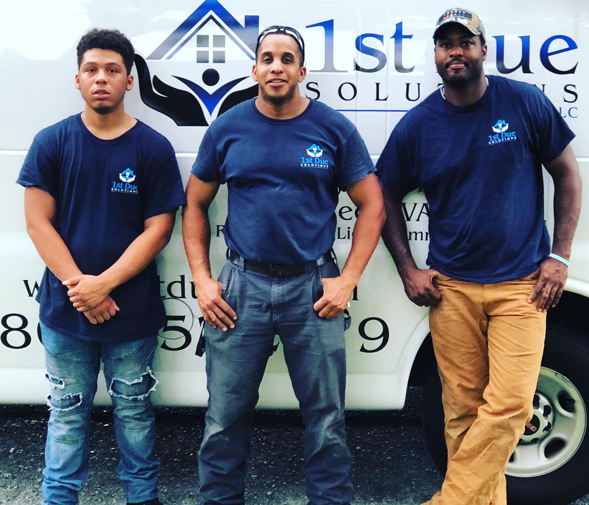 Three men standing in front of a van that says 1st solution