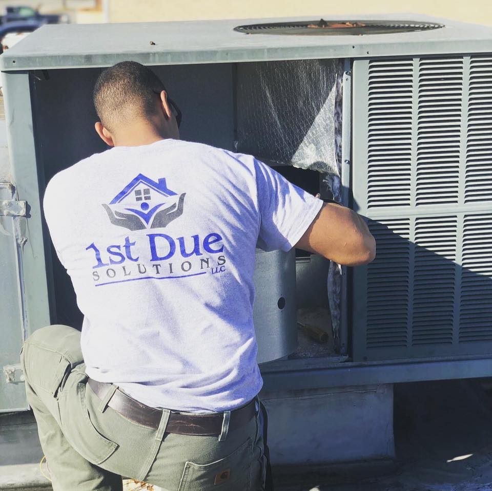 A man wearing a 1st due solutions shirt is working on an air conditioner