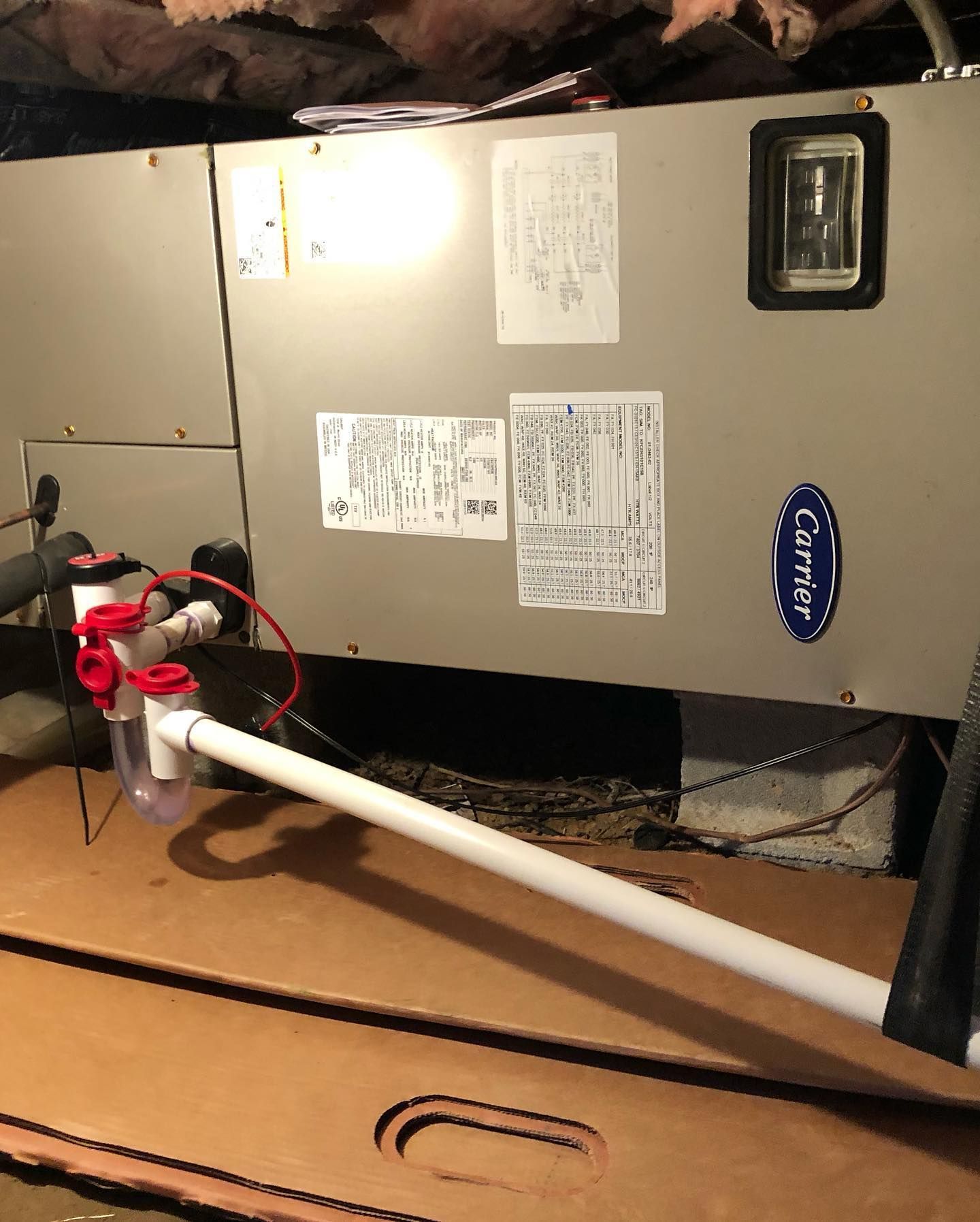 A carrier air conditioner is sitting on top of a cardboard box.