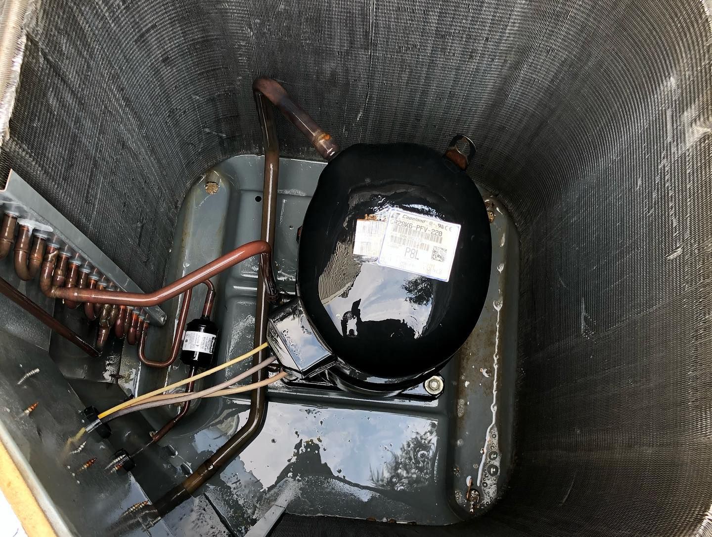 The inside of an air conditioner with a compressor and tubes.