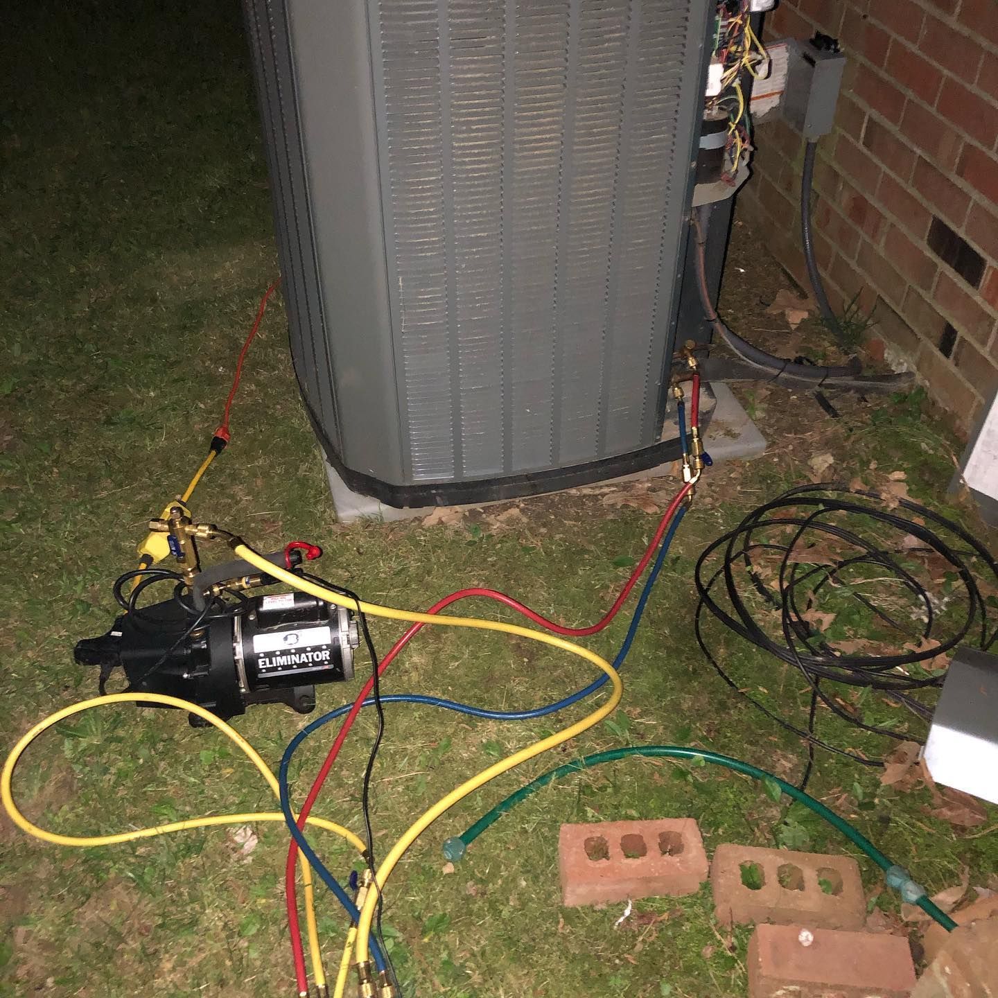 An air conditioner is being installed in a yard with a vacuum pump attached to it.