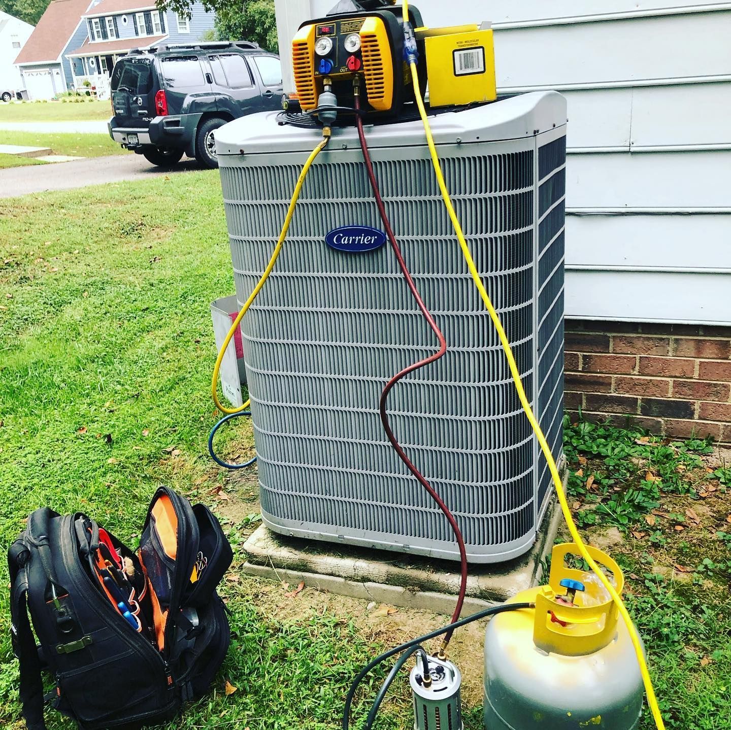 A carrier air conditioner is being serviced outside of a house.