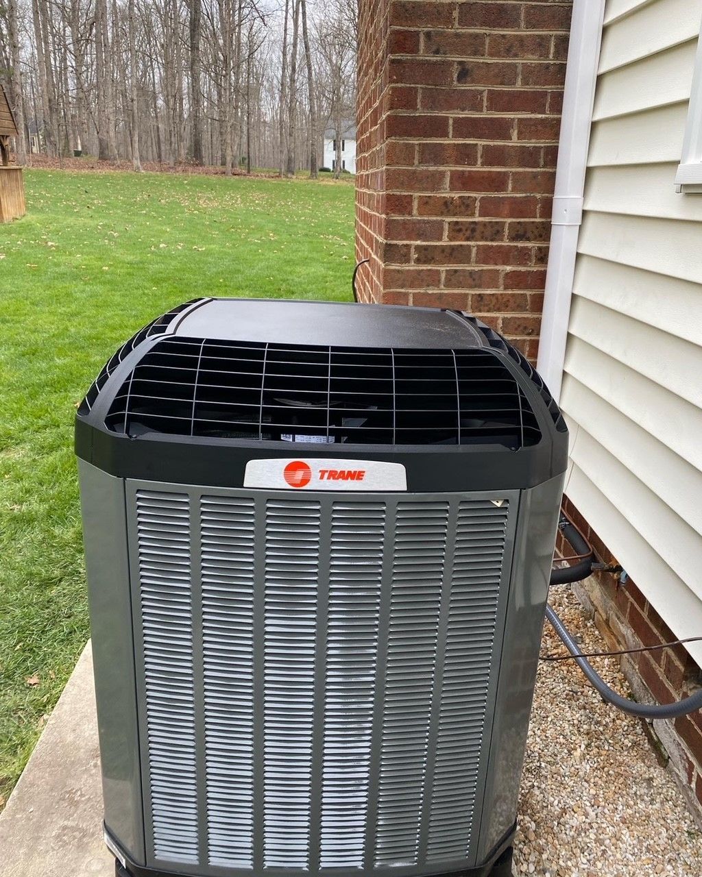 A trane air conditioner is sitting outside of a house