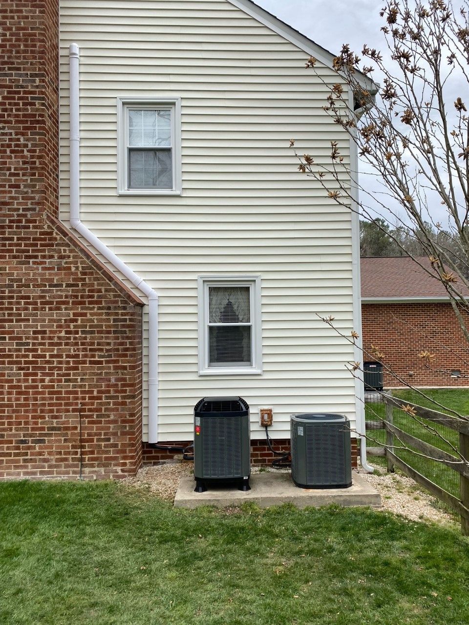 There are two air conditioners on the side of the house.