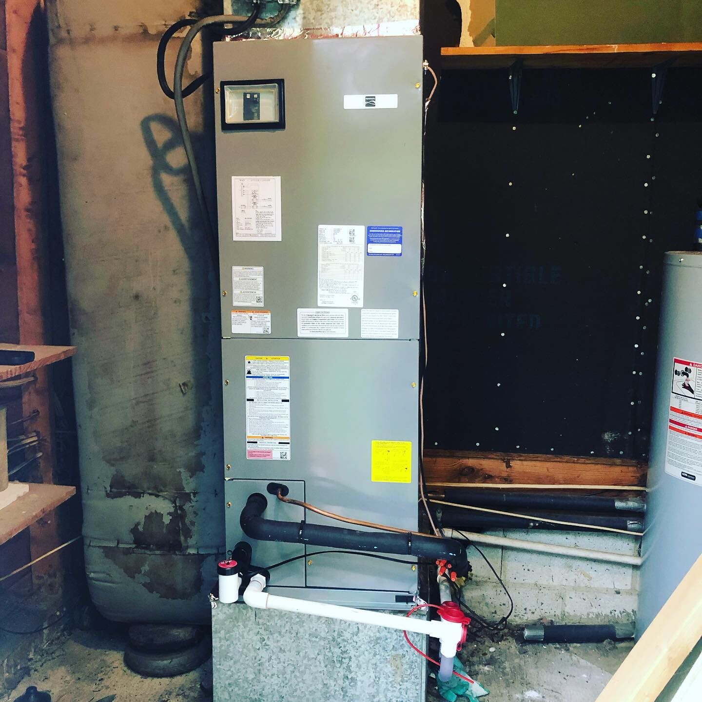 An air conditioner is sitting in a room next to a water heater