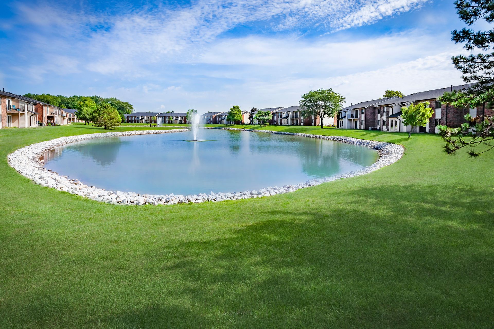 a large pond with a fountain in the middle of it at Greenfield Village.
