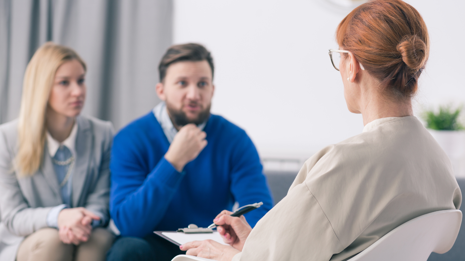 Couple in counseling session with therapist taking notes.