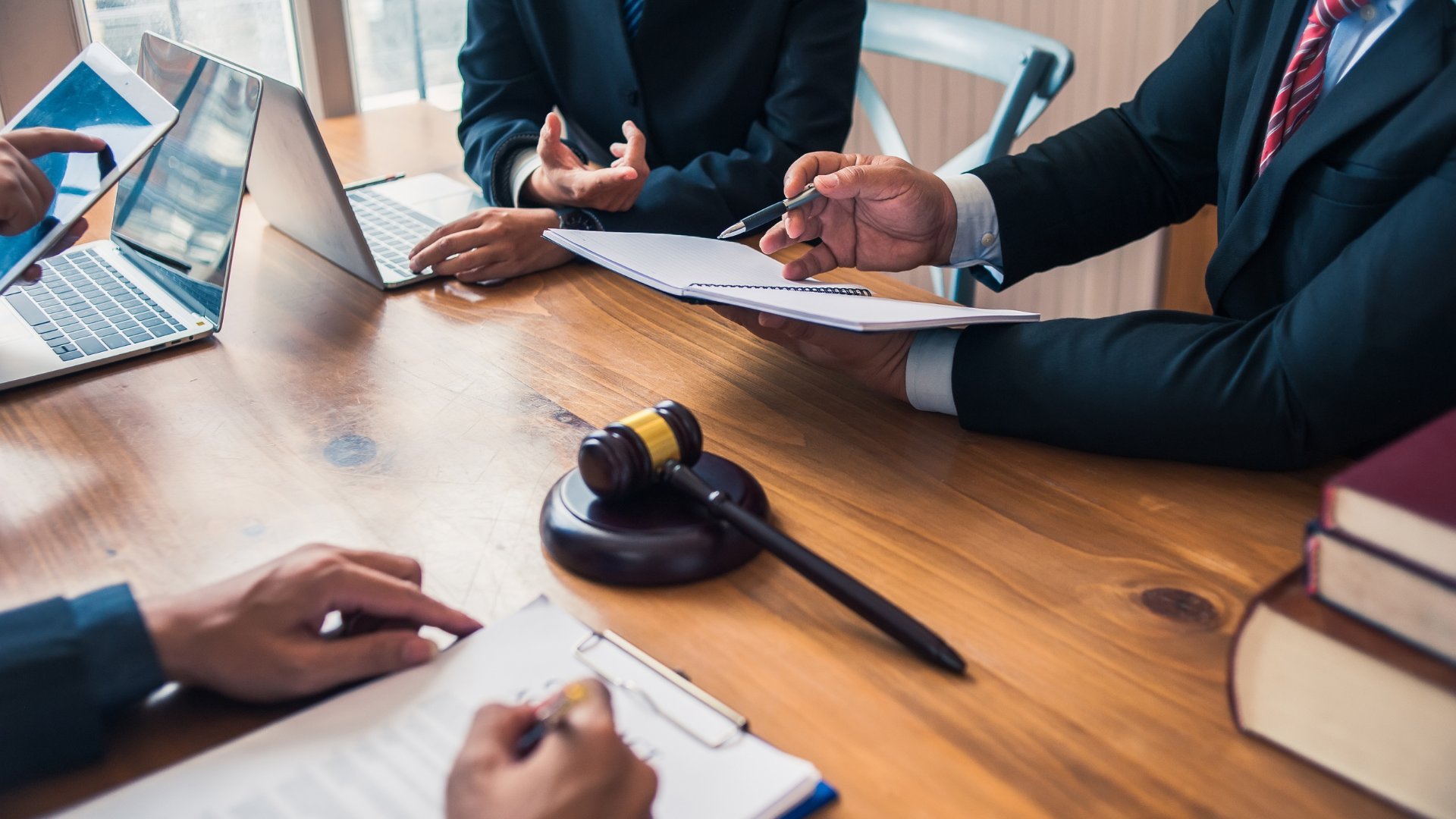 People in suits at a table, reviewing papers. A gavel and books are also on the table.
