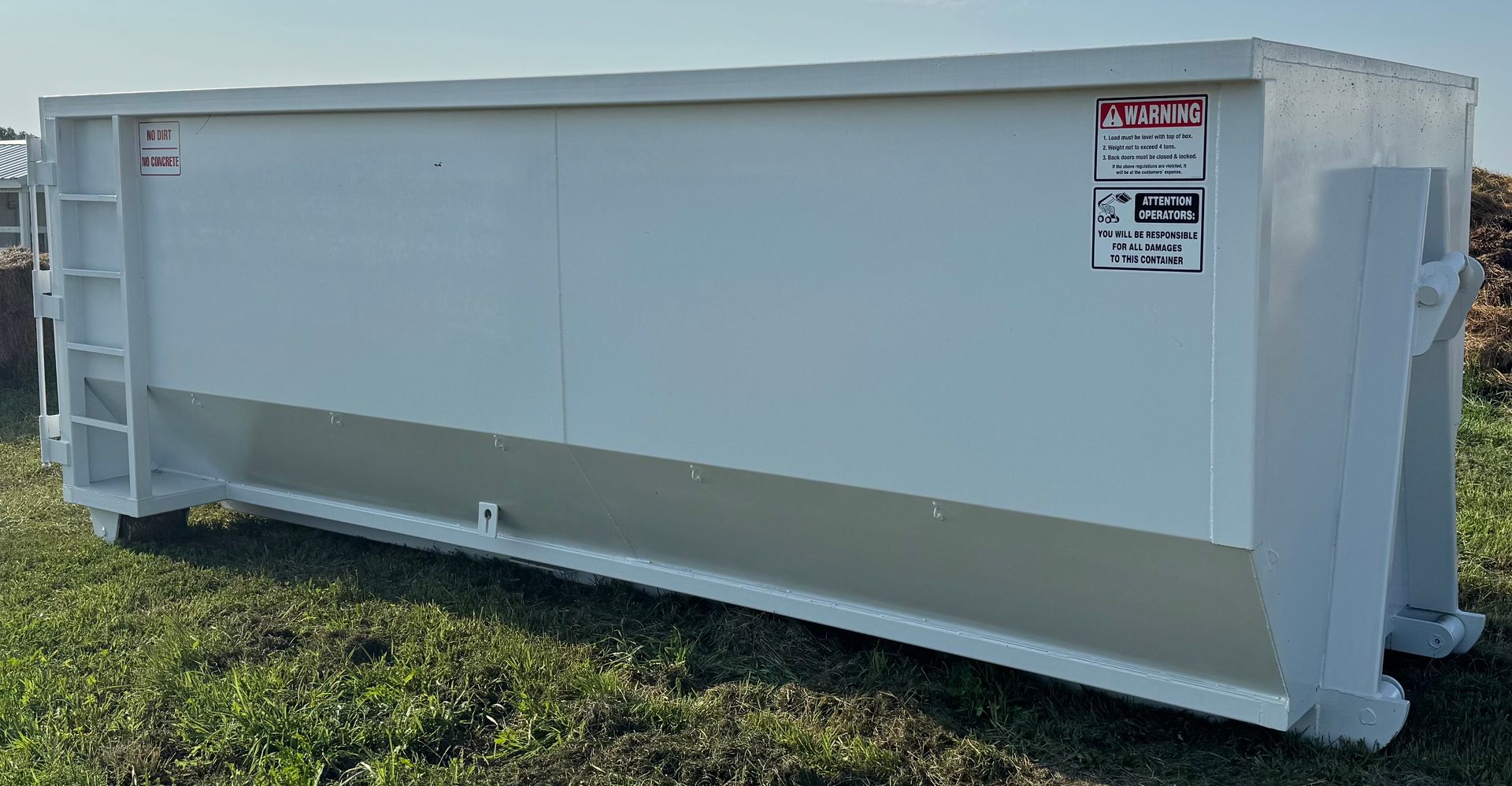 White industrial dumpster with a gray angled lower panel on grass.
