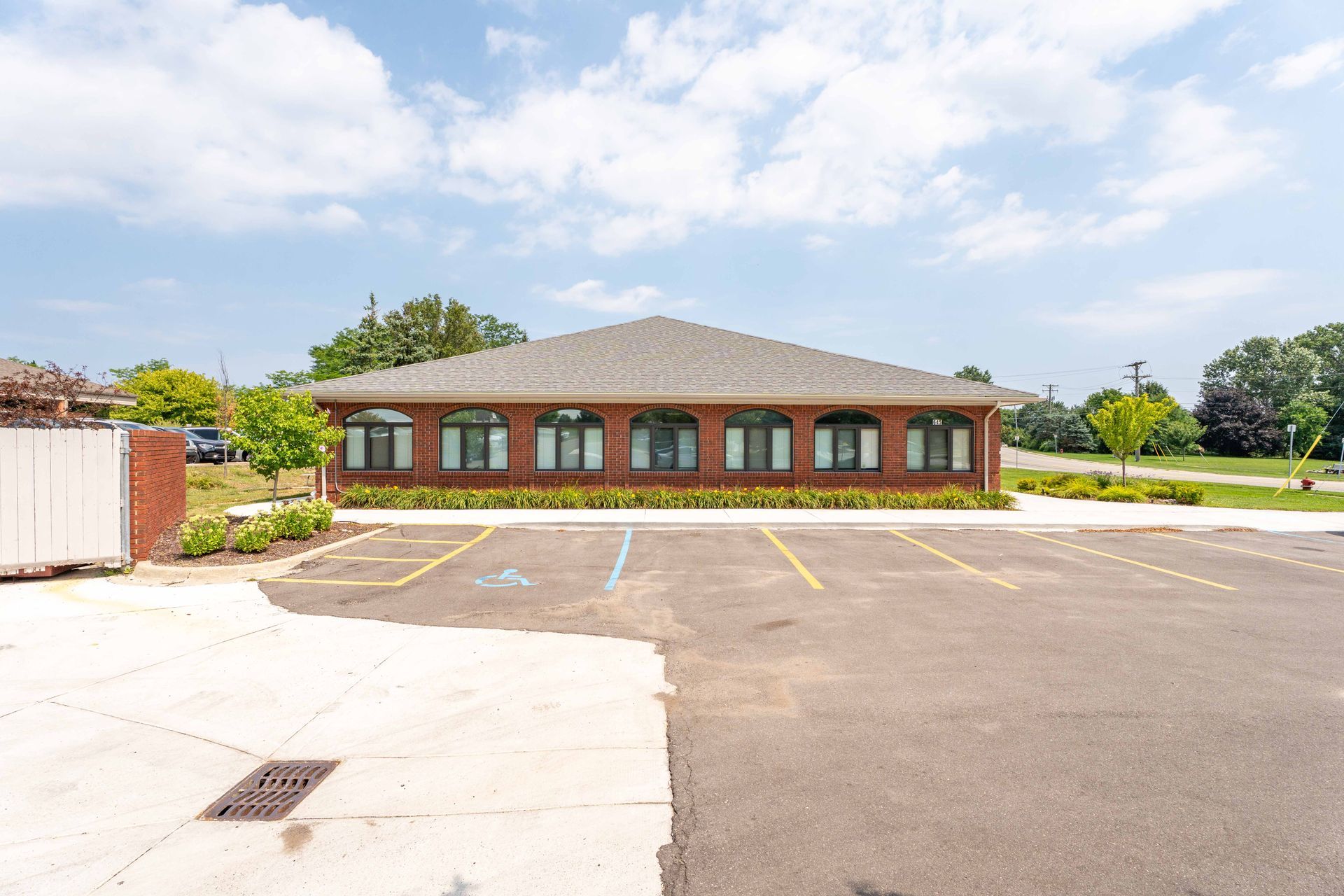 Red brick building with arched windows, parking lot, and blue sky.