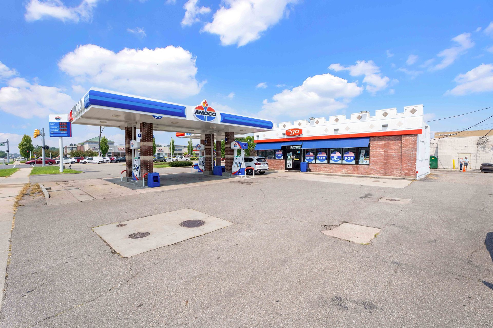 Gas station with blue and white canopy on a sunny day. Brick building with store front.