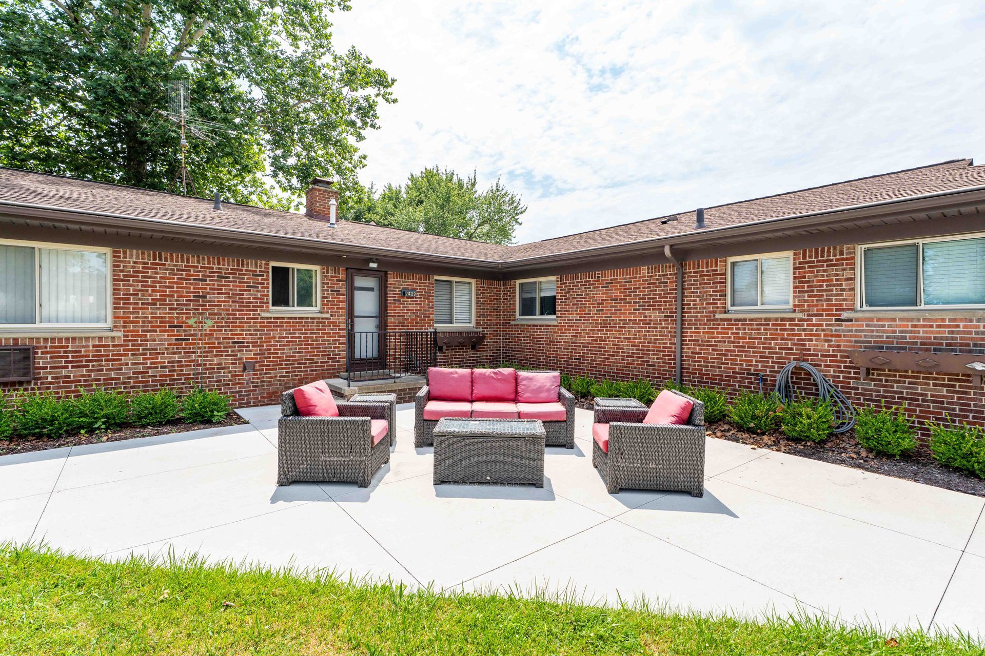 Outdoor courtyard with red brick buildings, patio furniture, and green grass.
