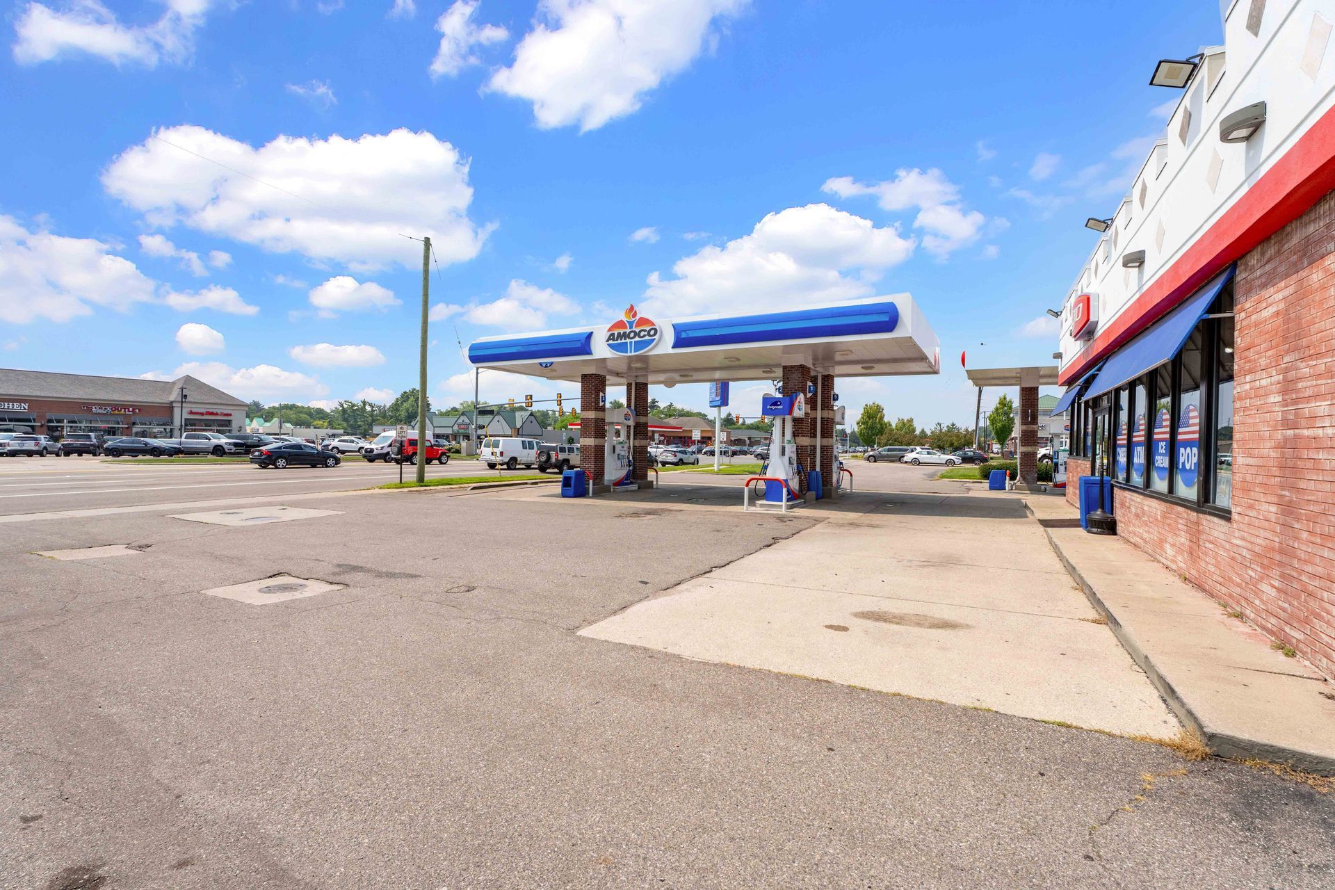 Gas station with blue canopy, red trim, and store on a sunny day.