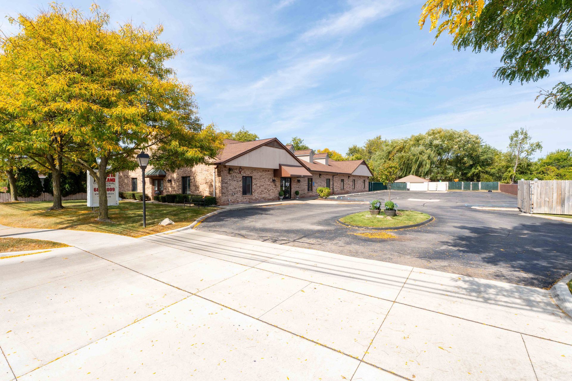 Brick building with a parking lot and trees. Blue sky.