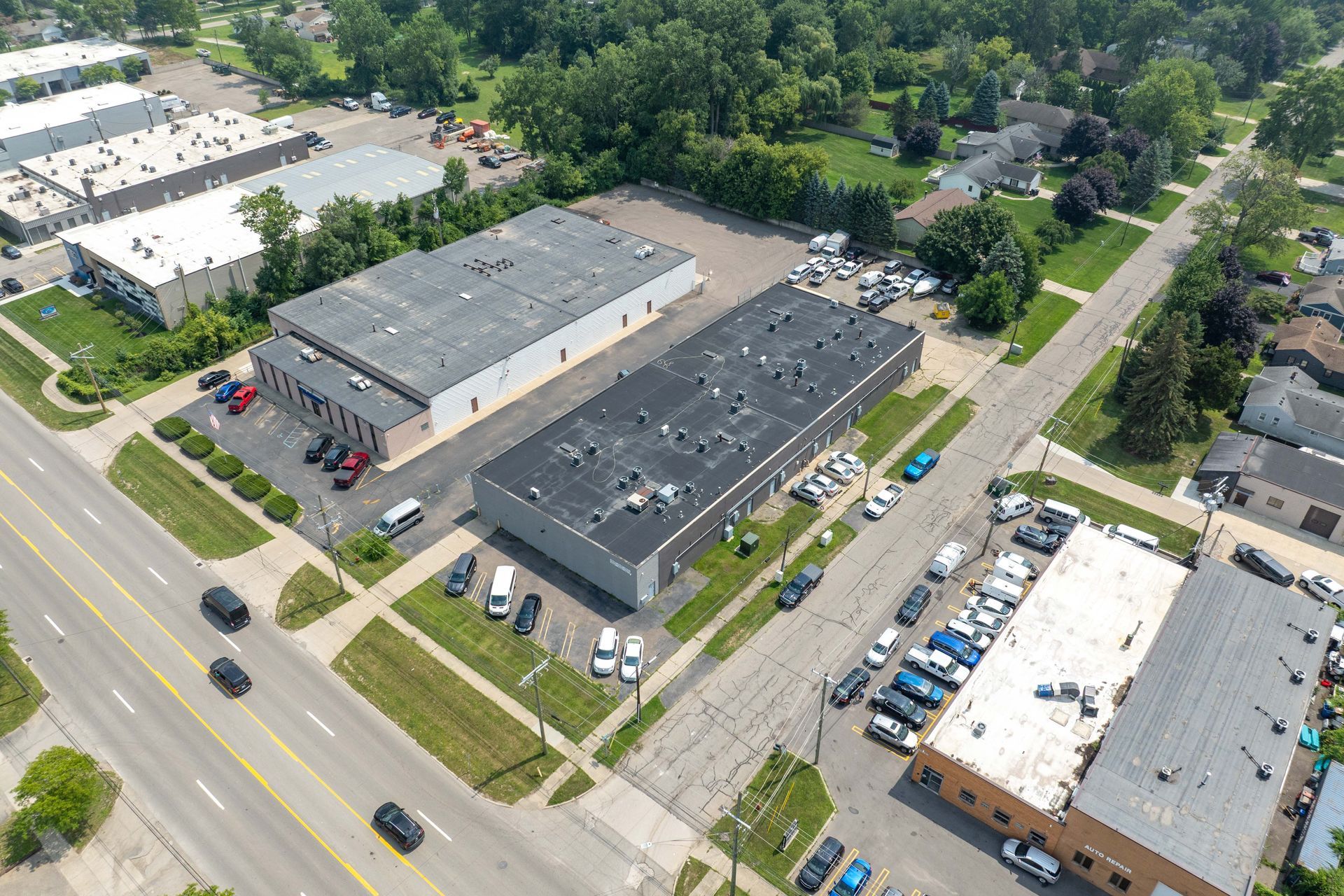 Aerial view of commercial buildings, roads, and parked vehicles on a sunny day.