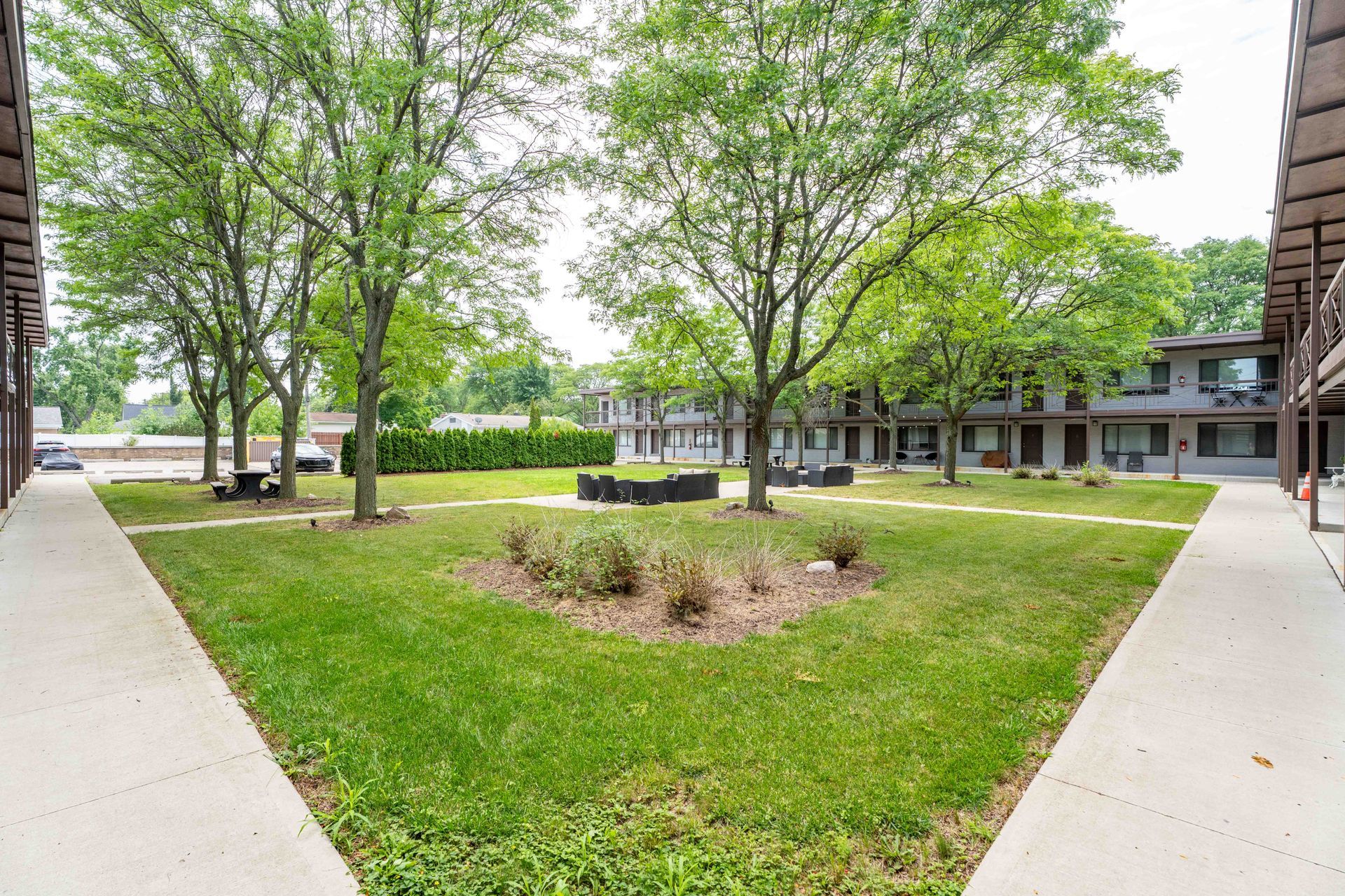 Courtyard with grass, trees, and buildings on either side.