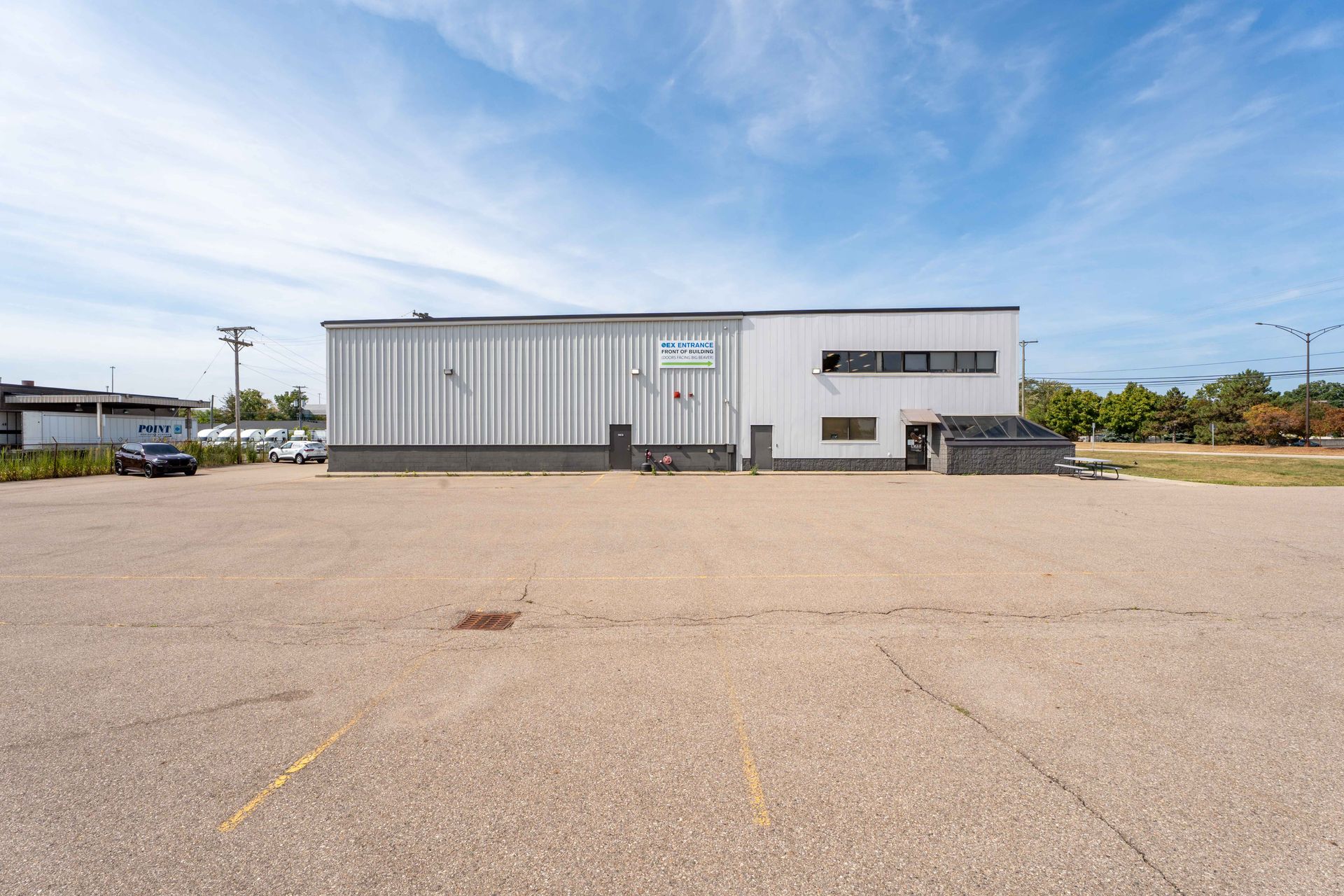 Warehouse building with a large paved parking lot under a blue sky.