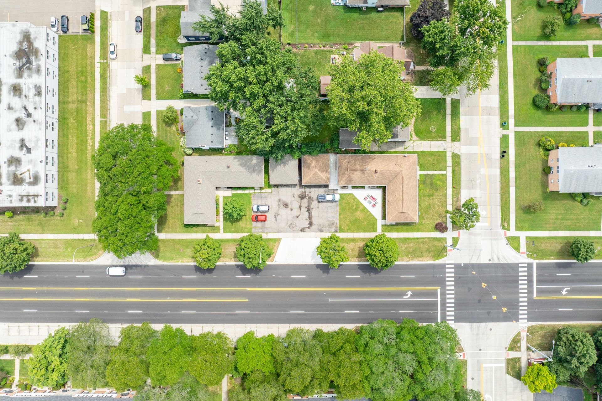 Aerial view of residential neighborhood with streets, trees, houses, and cars.