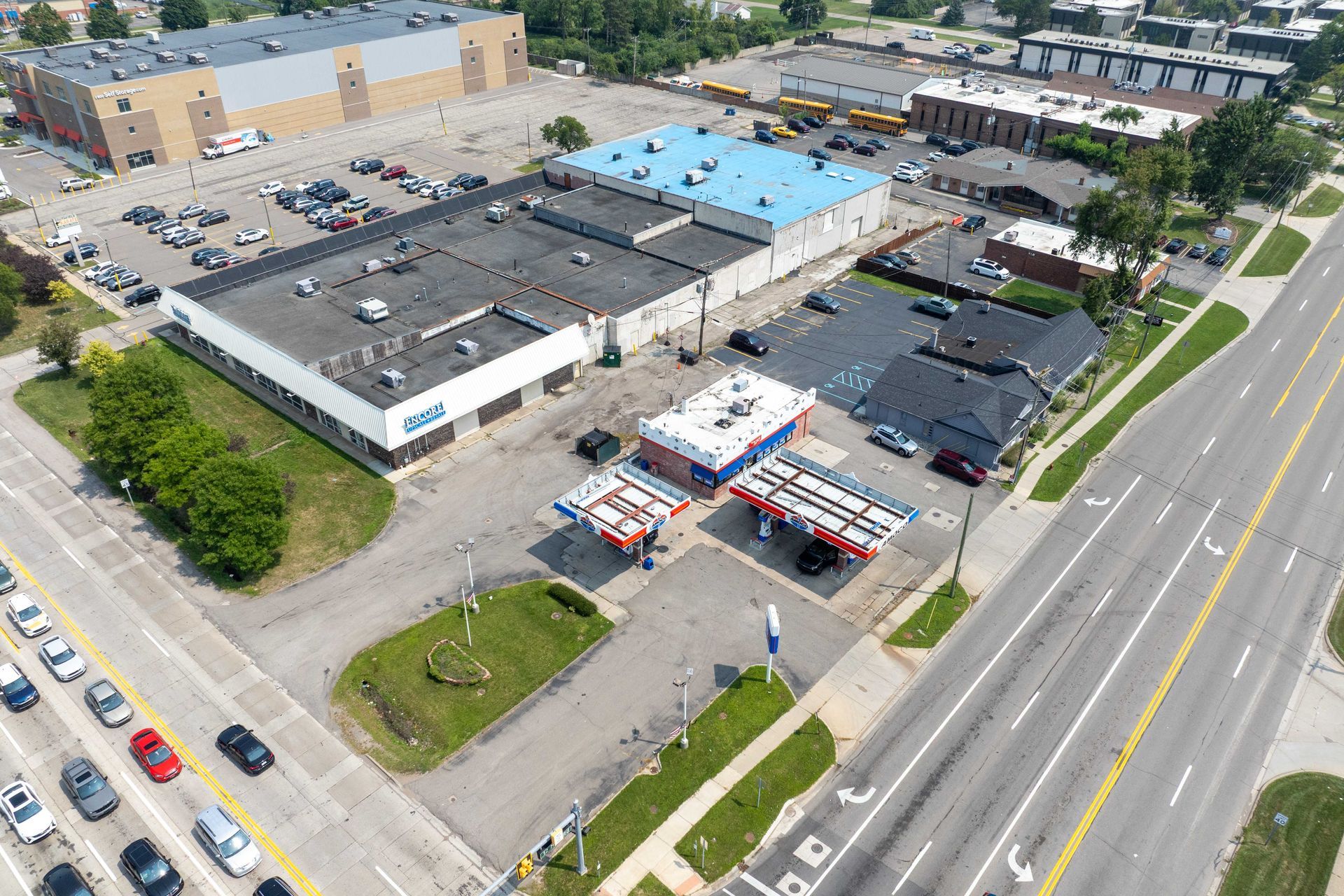 Aerial view of commercial buildings, gas station, and road with traffic.