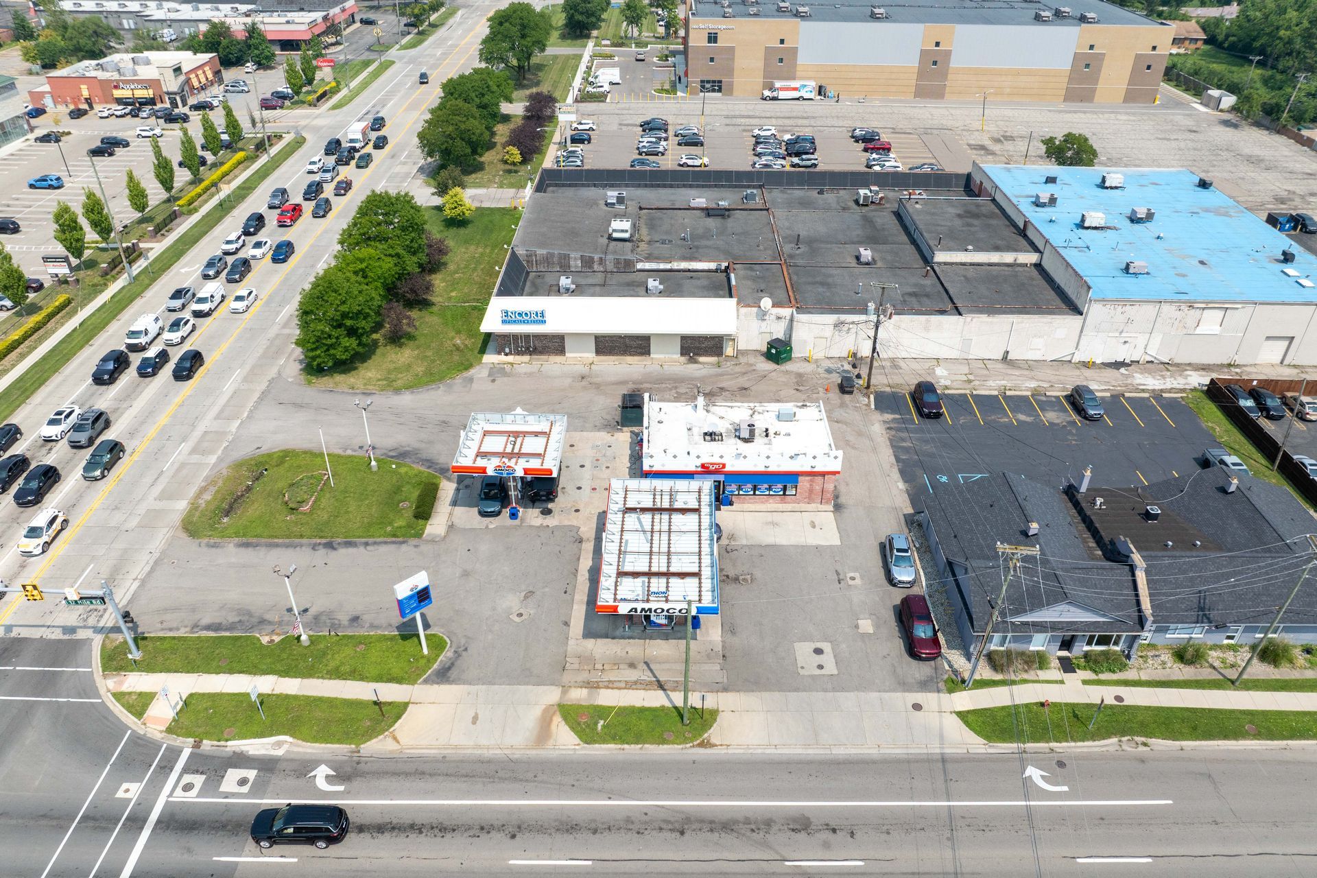 Aerial view of a gas station and buildings. Cars on a multilane road. Green grass and asphalt.