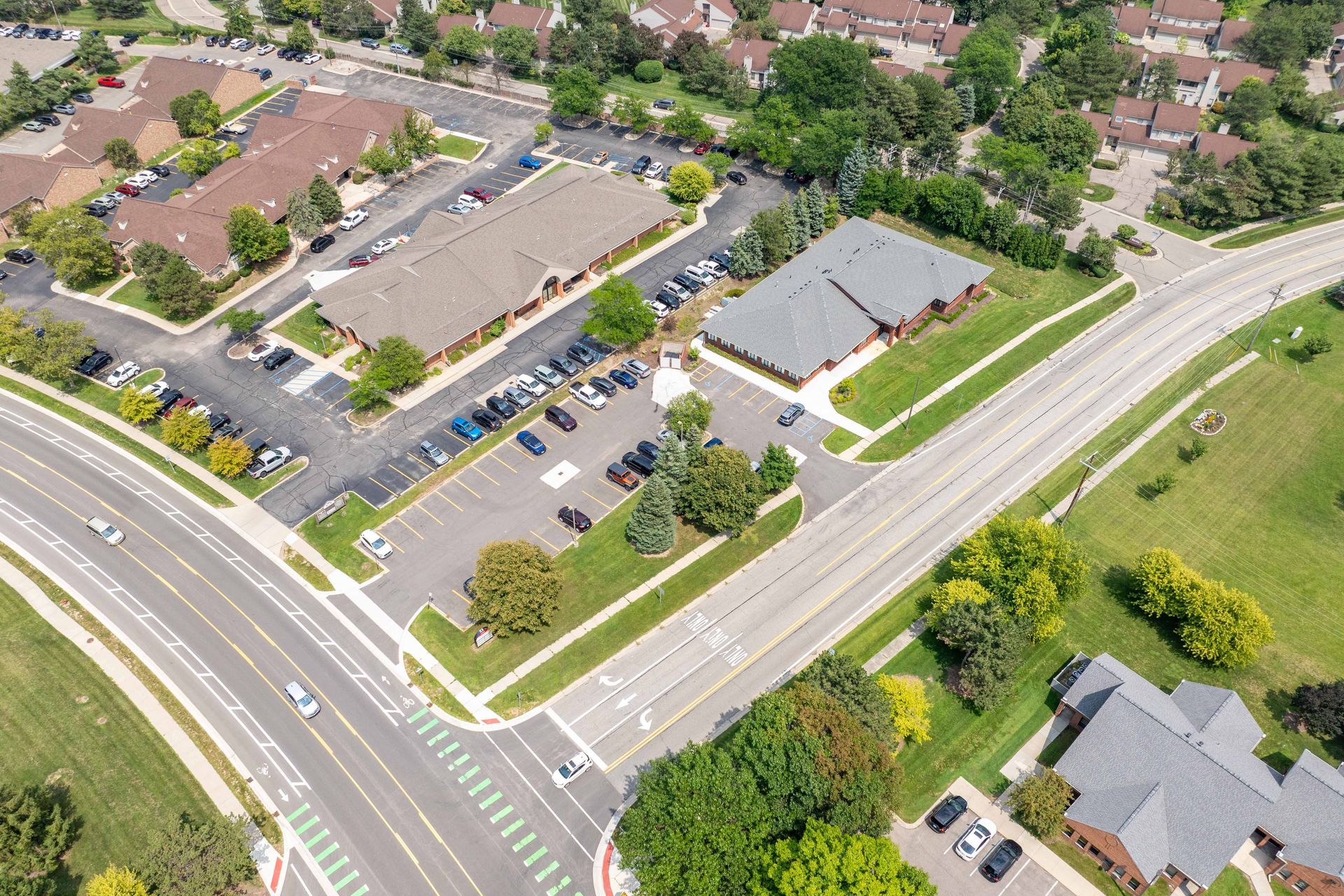 Aerial view of commercial buildings, parking, and a road.