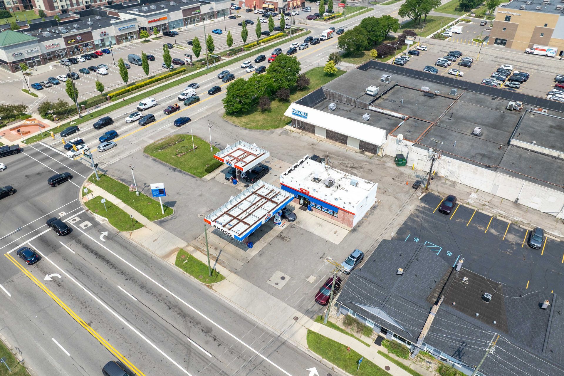 Aerial view of a gas station and surrounding buildings with cars on the road.