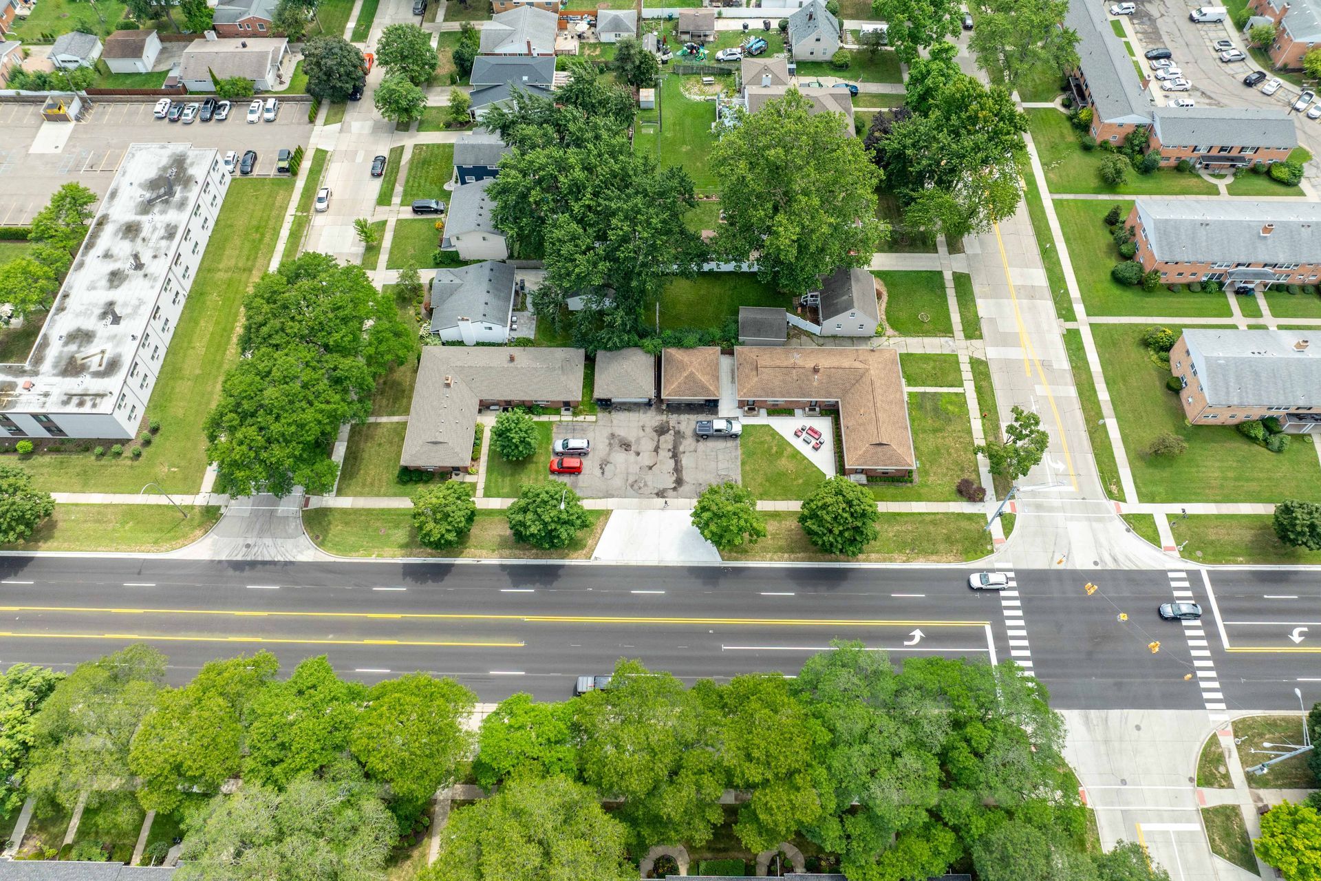 Aerial view of a neighborhood with houses, trees, and a road with crosswalks.
