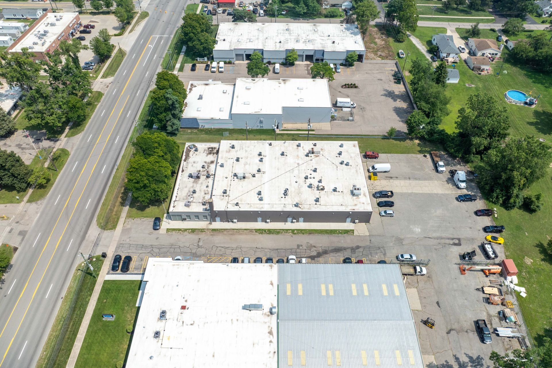 Aerial view of industrial buildings, parking lots, and a road; daytime.