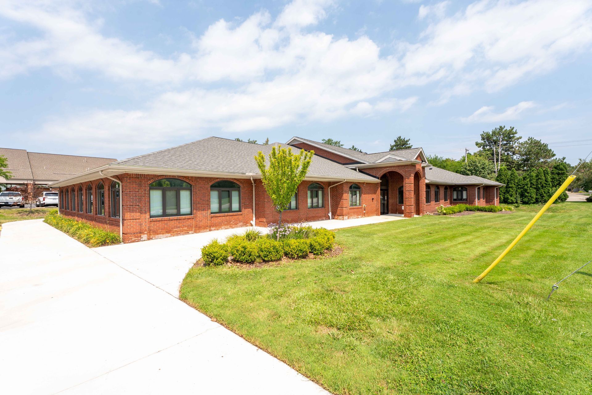 Red brick building with arched entrance, on a grassy lawn. Concrete path leads to the door.