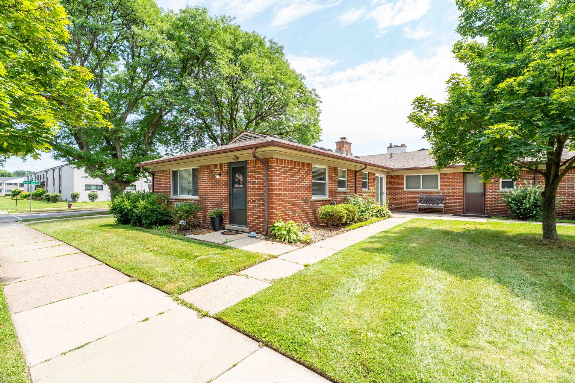 Brick building with green lawn and trees, pathway.