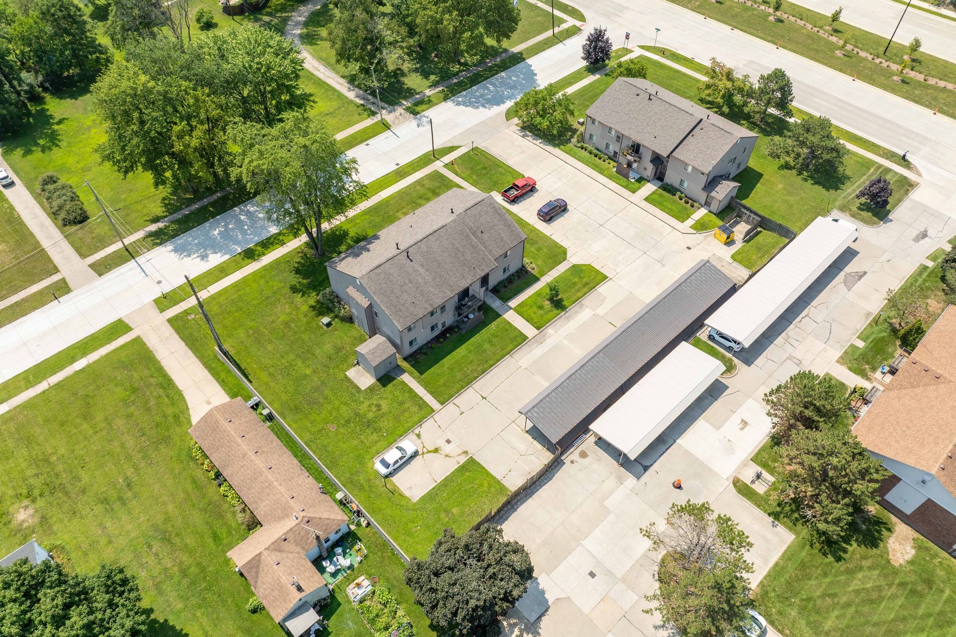 Aerial view of apartment buildings with parking, sidewalks, and green lawns.