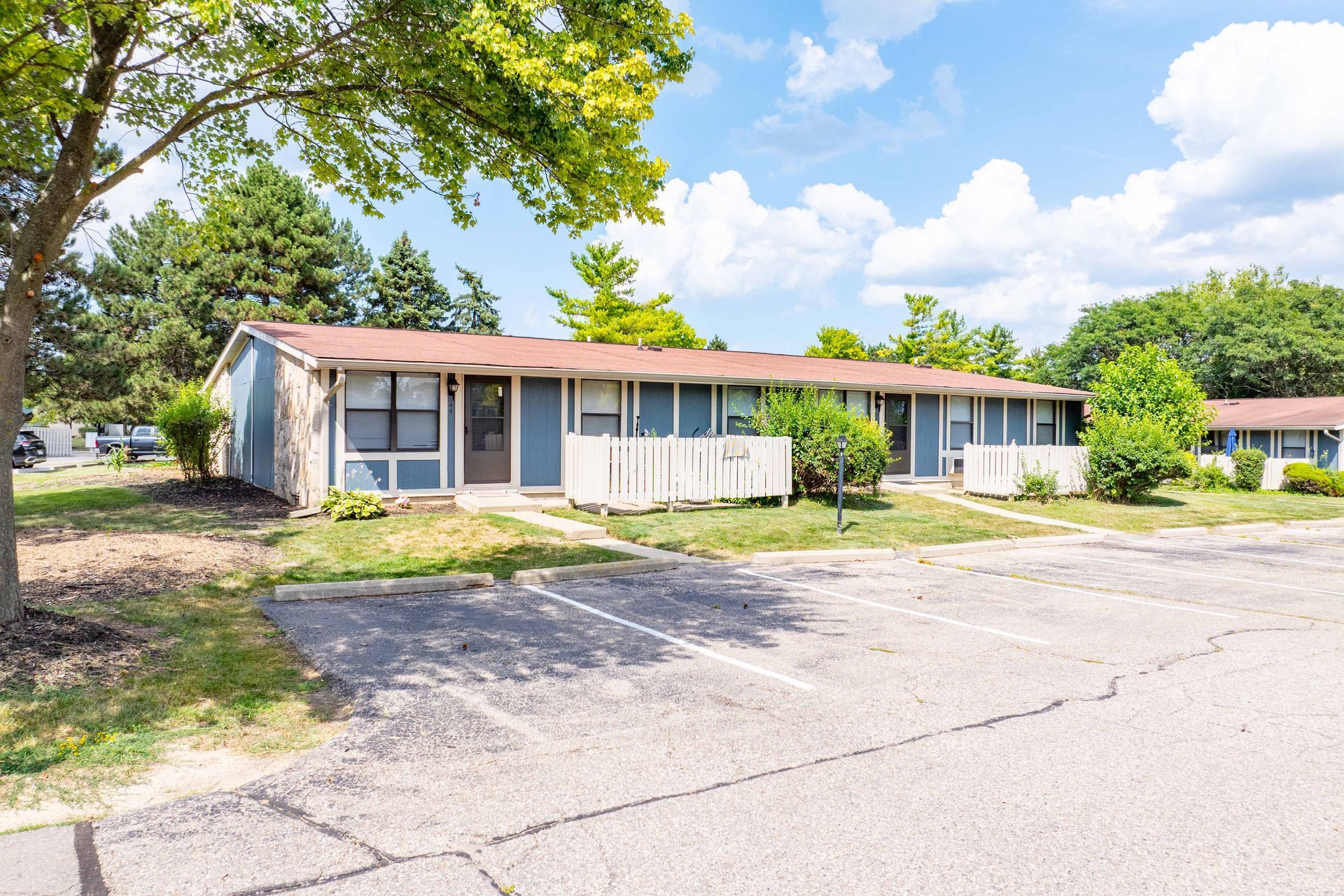 Blue apartment buildings with parking lot on a sunny day.