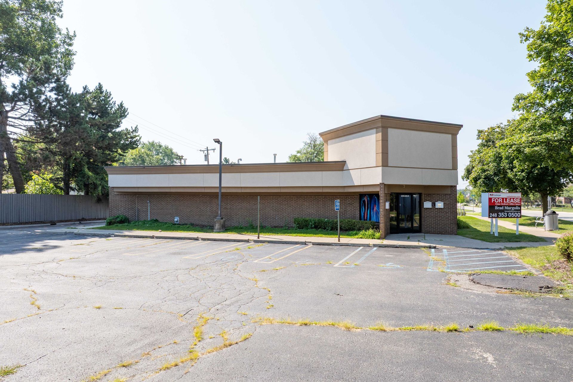 Exterior of a one-story commercial building with a cracked parking lot. A sign for 